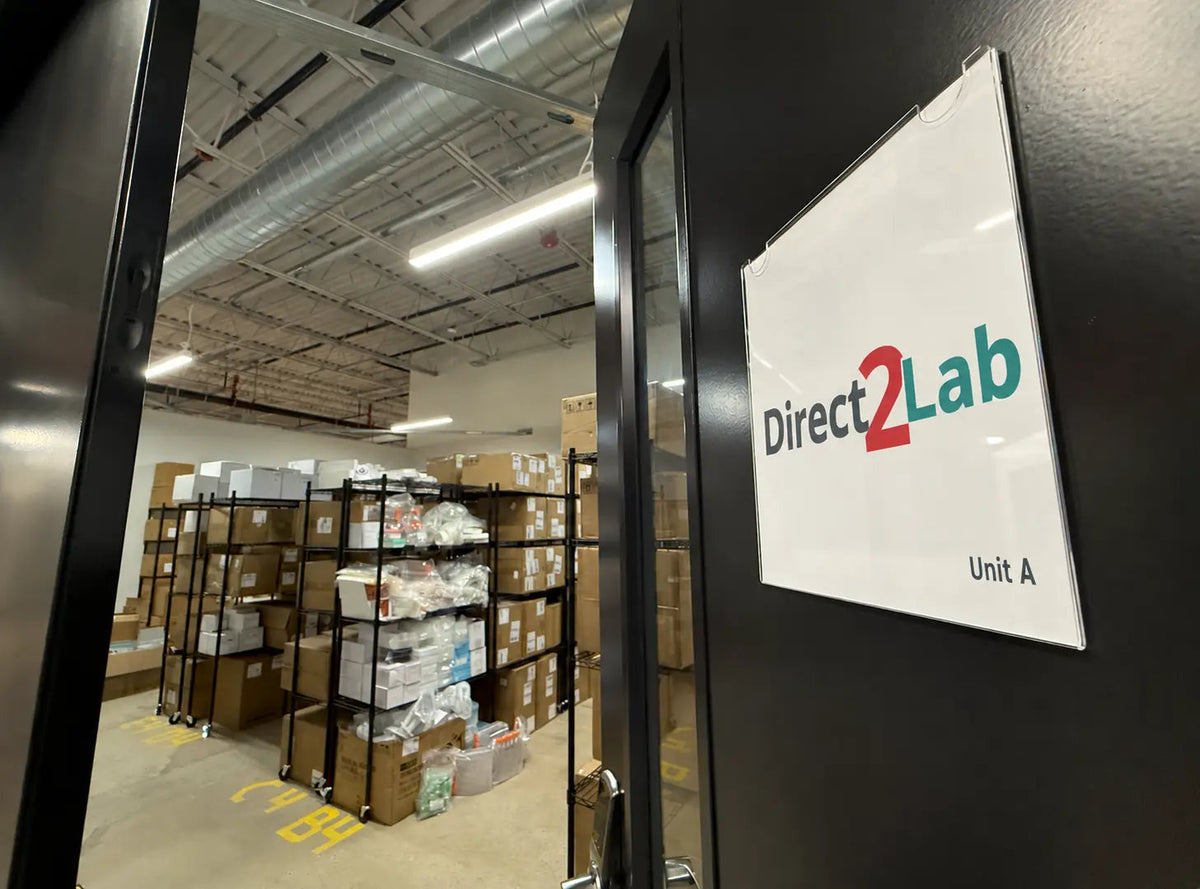 Direct2Lab sign beside the entrance to a warehouse with stocked shelves in Newton, Massachusetts.